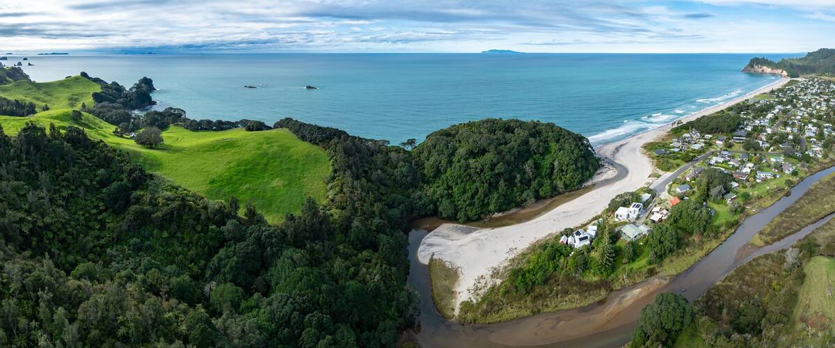 A coastal landscape with a beach, a river, and a residential area.