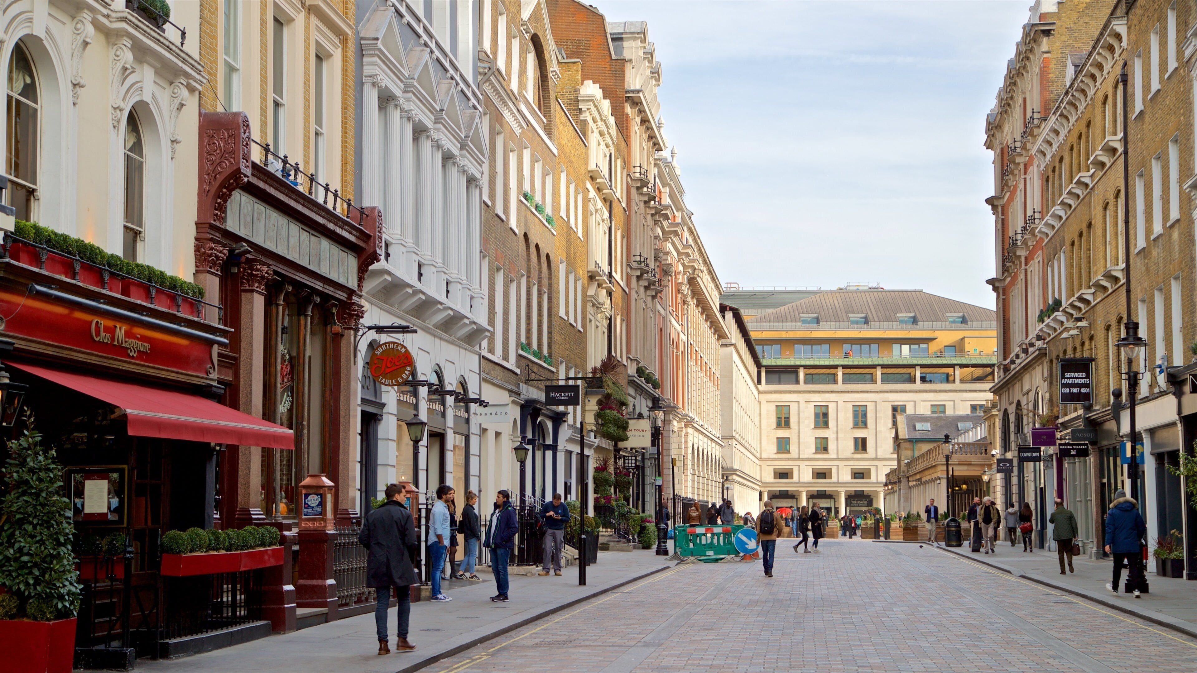 A historic European street lined with traditional buildings, cafes, and shops.