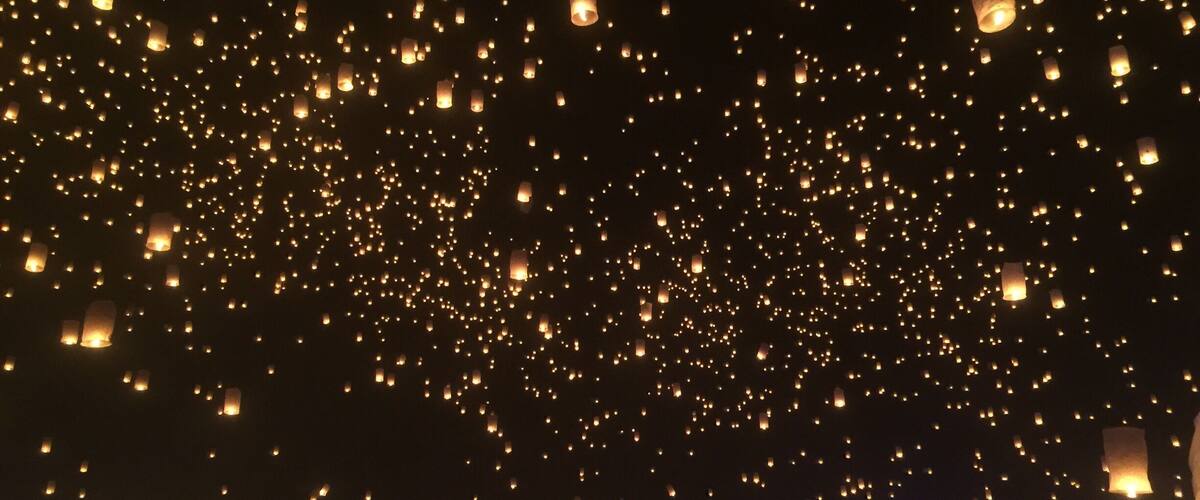 A night sky filled with numerous lanterns being released.