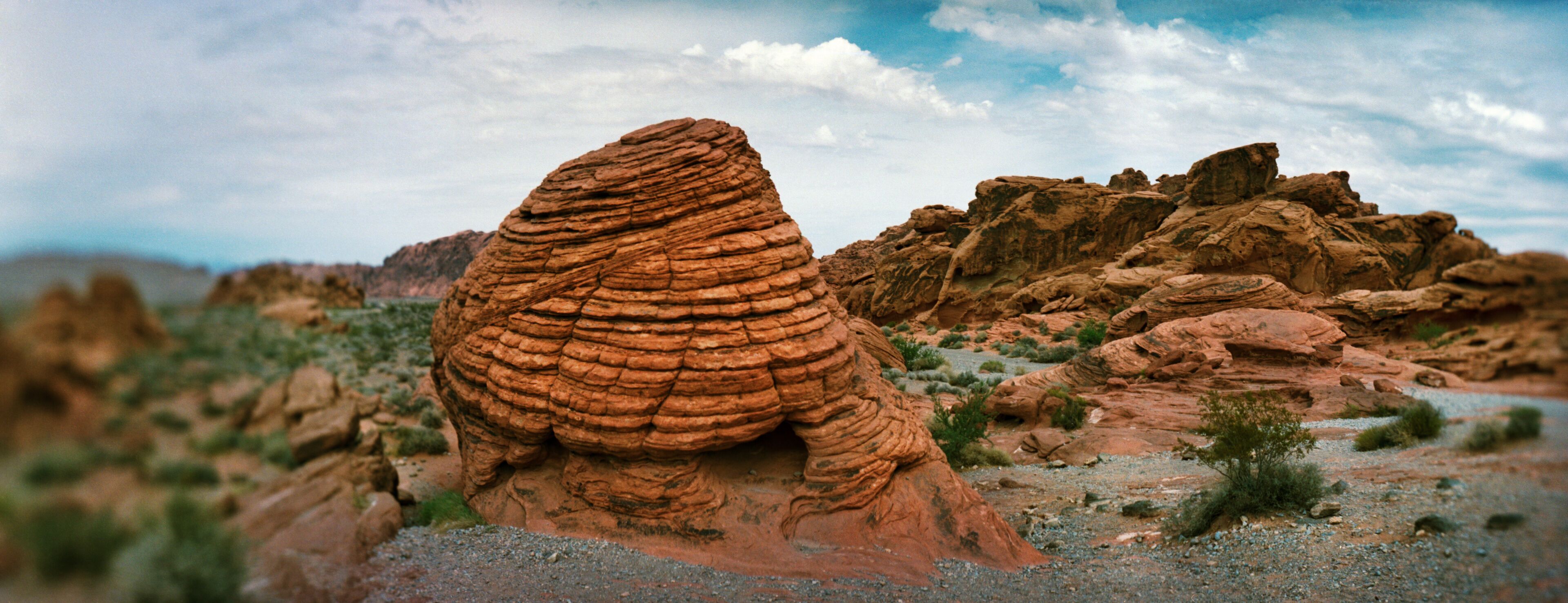 A large, layered rock formation in a desert landscape.