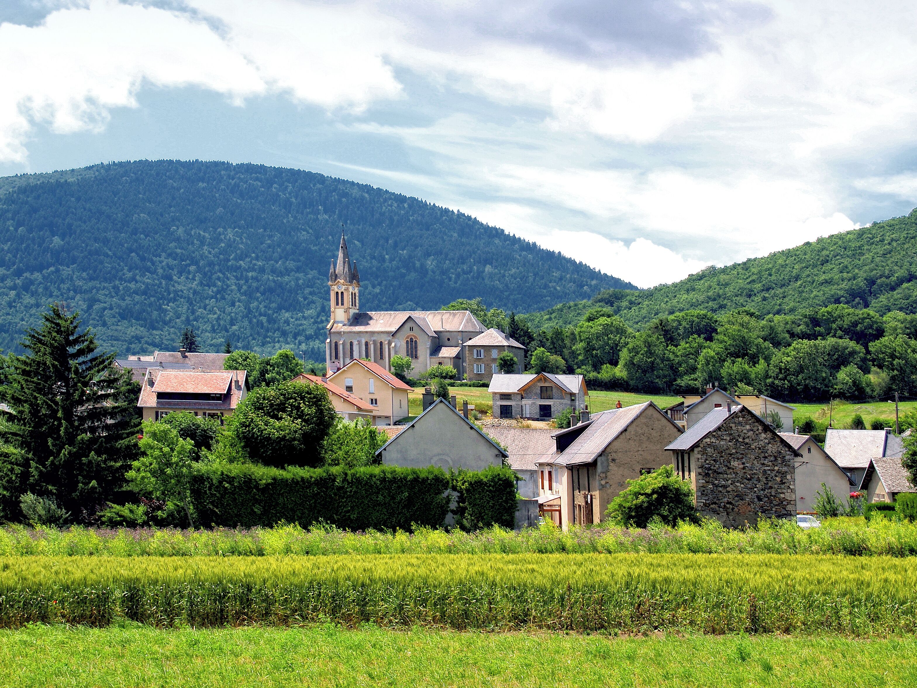A village with a church, houses, and a mountain in the background.