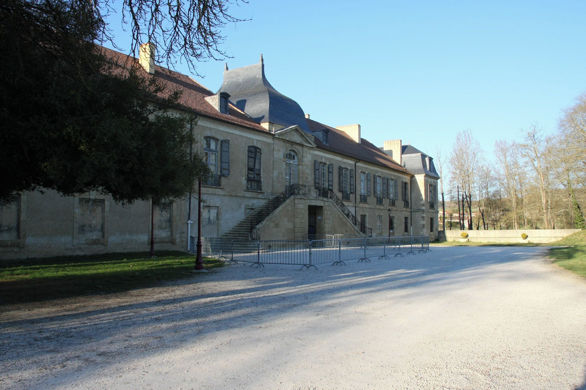 A historic building with a steep staircase and a gravel driveway.
