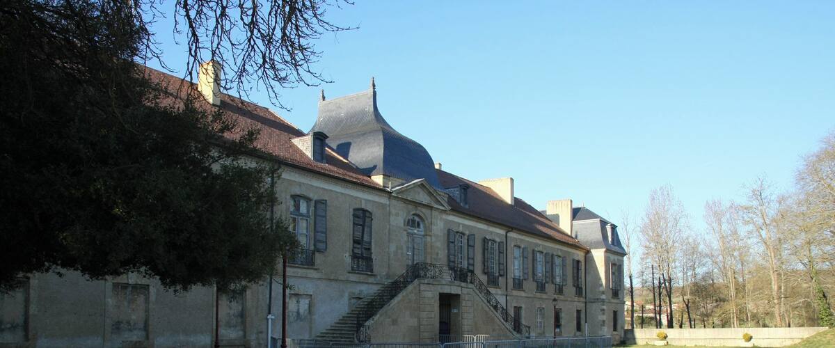 A historic building with a steep staircase and a gravel driveway.