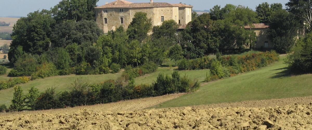 A stone building surrounded by trees and fields.