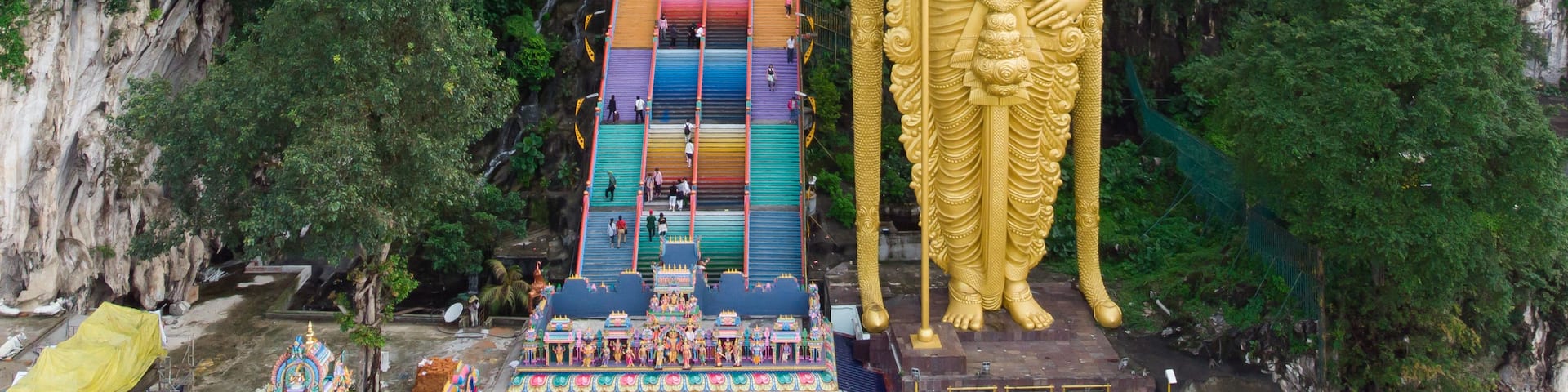 A large golden statue of a deity, a colorful staircase, and a temple with intricate architecture.