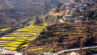 Terraced fields, a village with traditional houses, and a mountainous landscape.