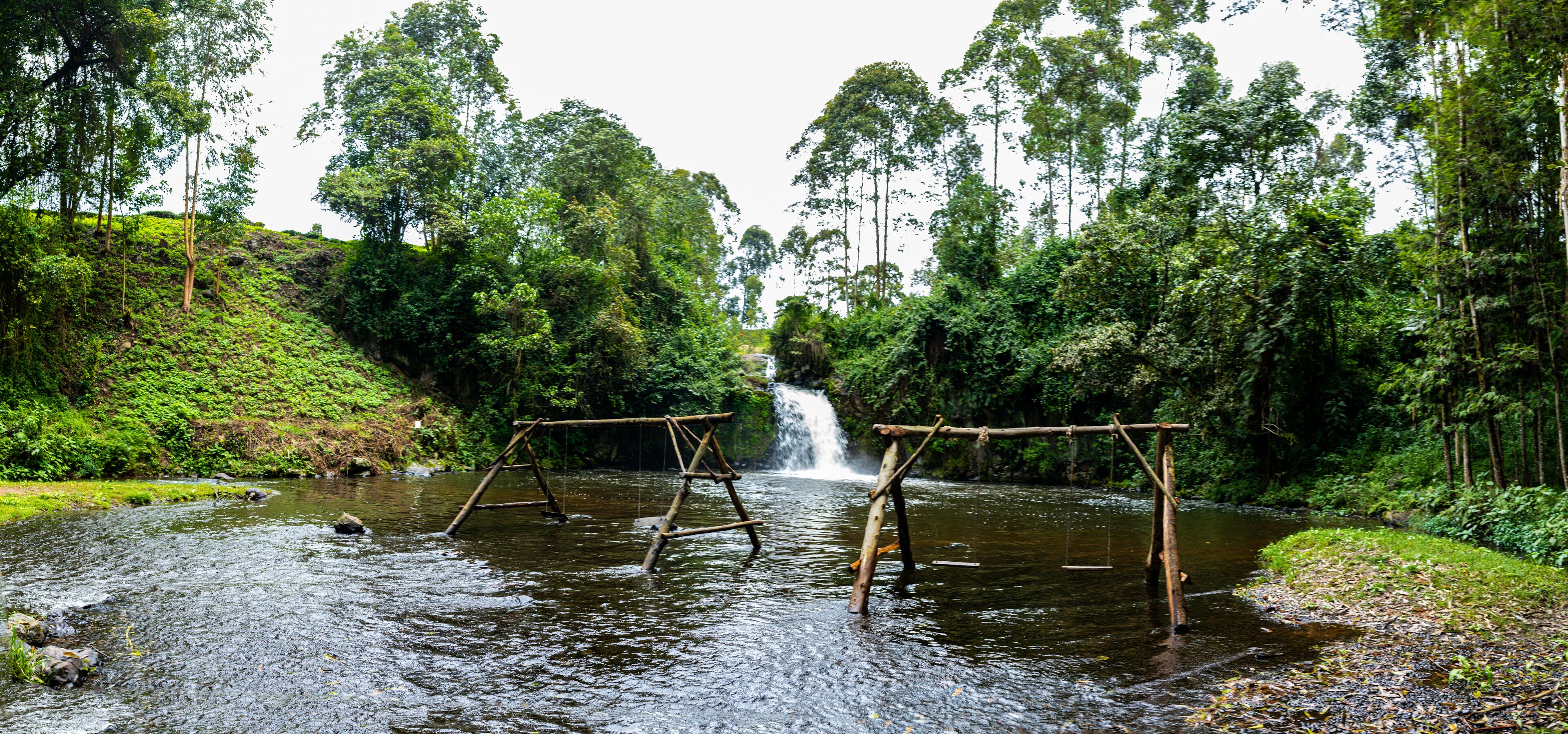 A river with wooden swings and a waterfall in a forested area.
