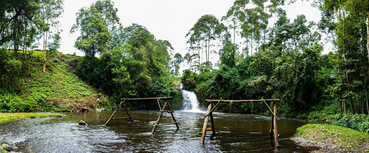 A river with wooden swings and a waterfall in a forested area.