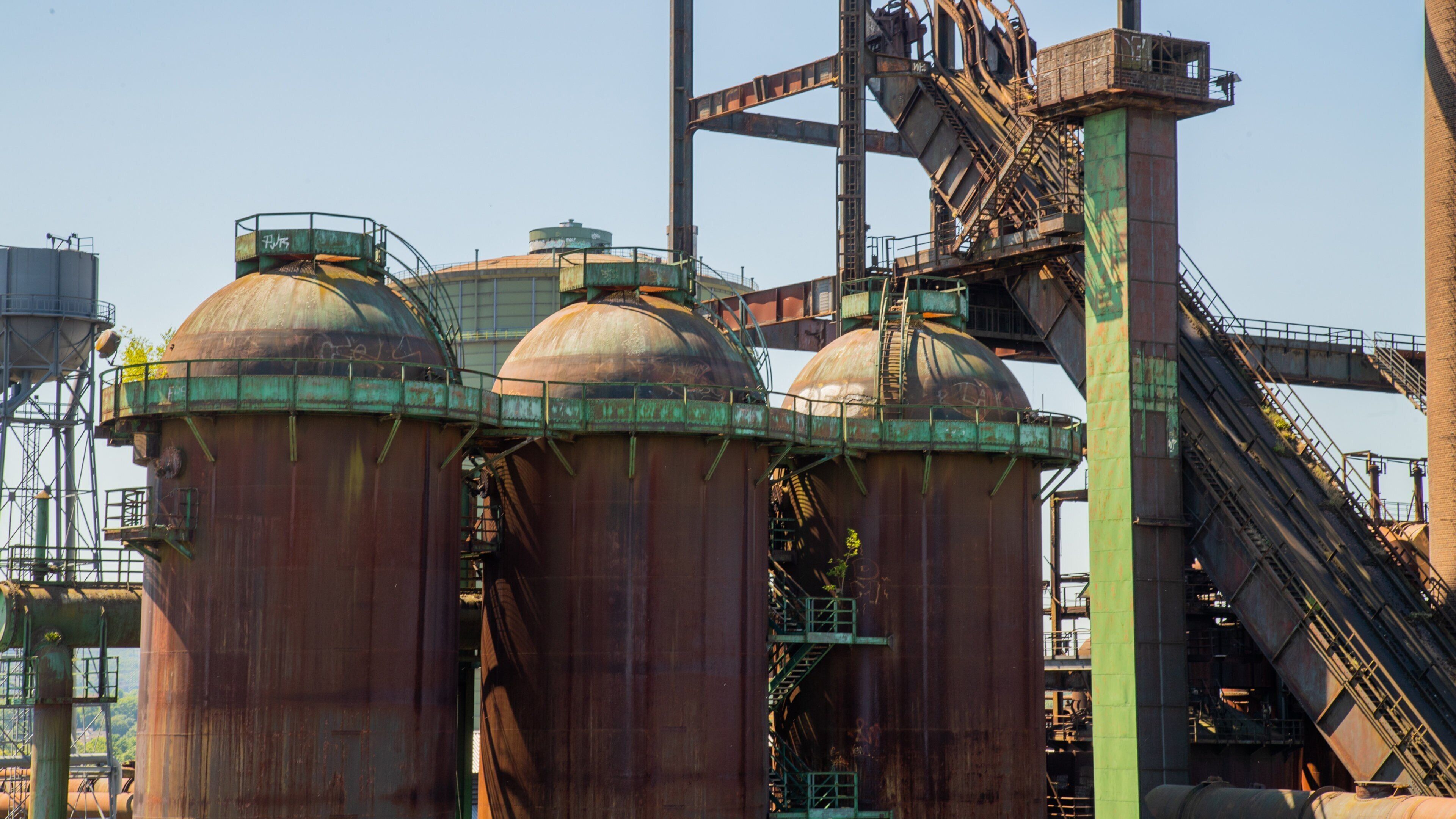Large industrial silos with green tops and a conveyor belt system.