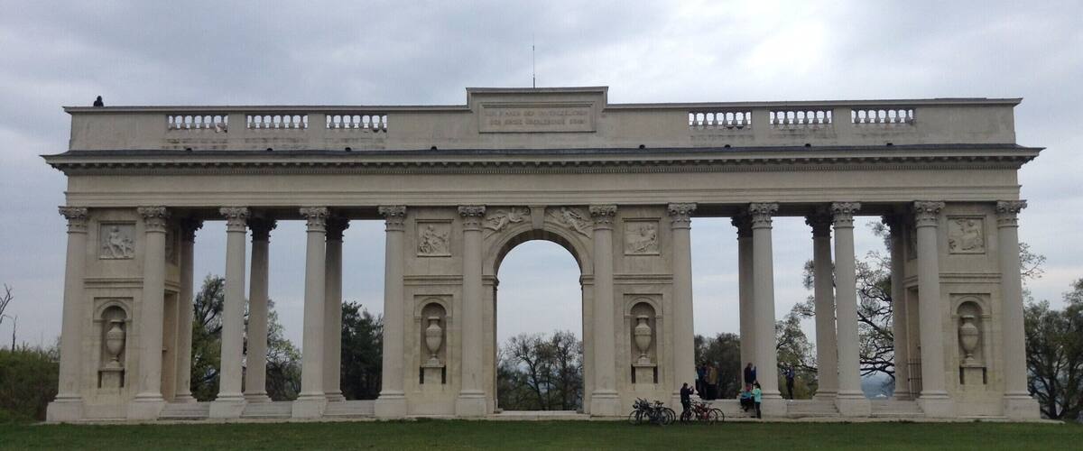 A large neoclassical archway with columns and decorative elements.