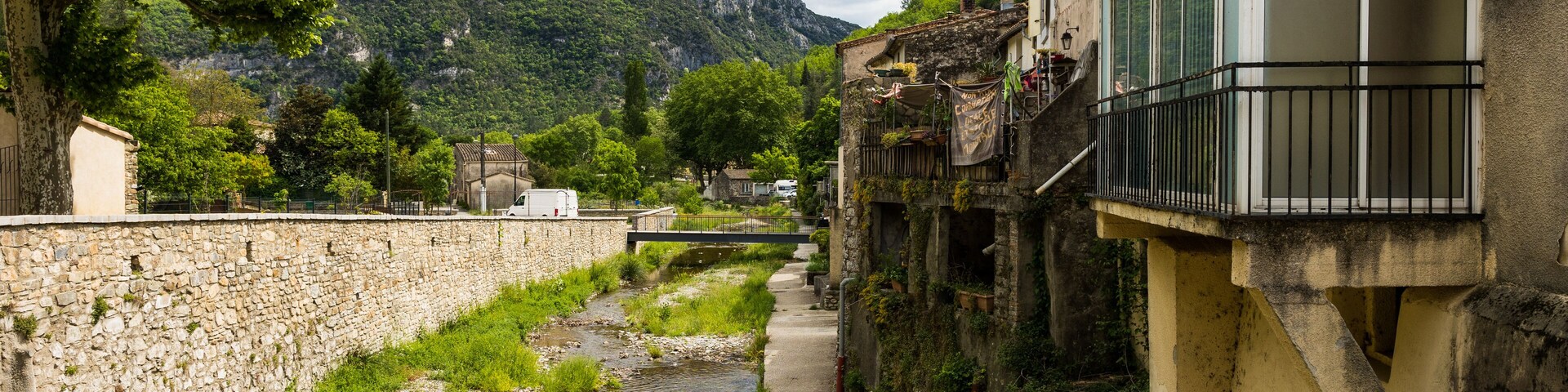 Un canal estrecho bordeado por muros de piedra y edificios, con una montaña al fondo.