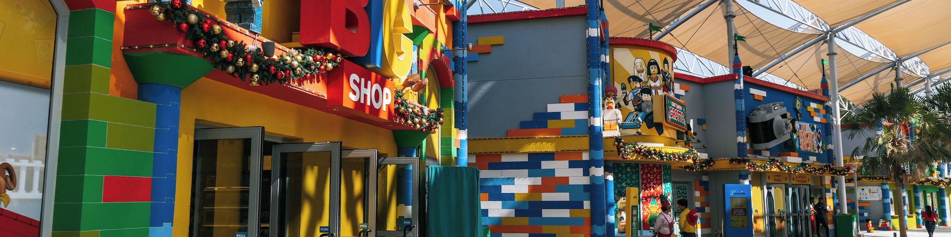 Een kleurrijk gebouw met een gevel in LEGO-thema, een winkelbord en een grote luifel.