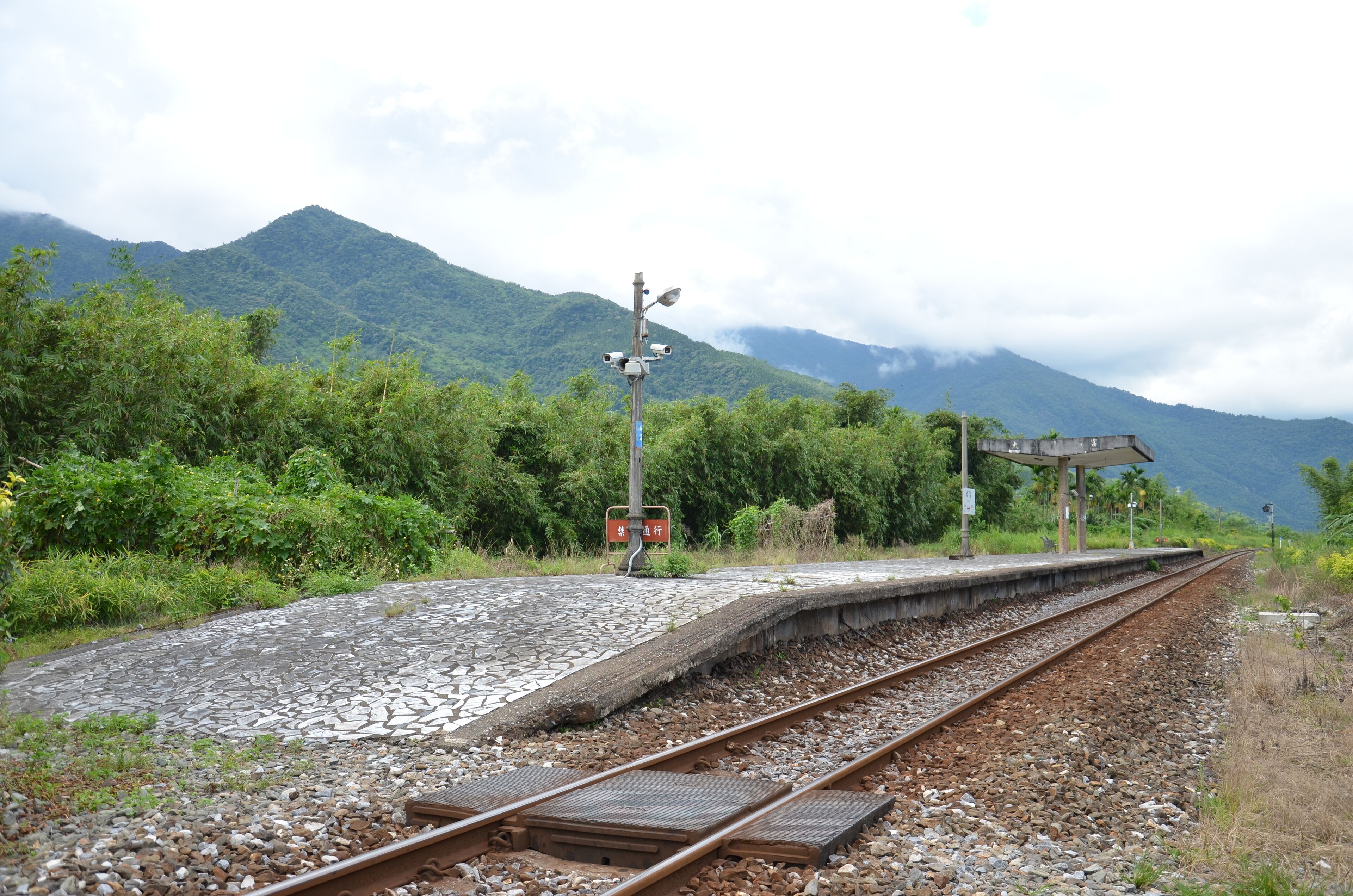 A railway track with a signal post and a shelter.