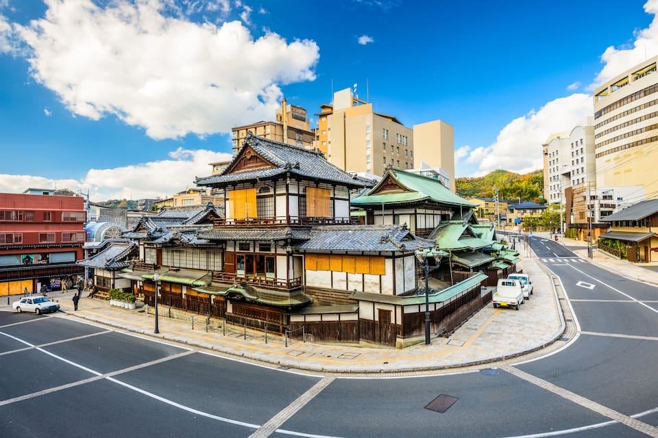 Un edificio japonés tradicional con tejado curvo, situado en una intersección urbana.