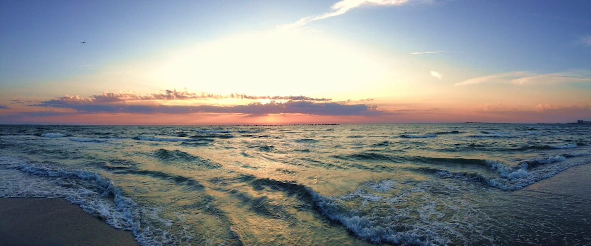 A sunset over the ocean with waves crashing onto the shore.