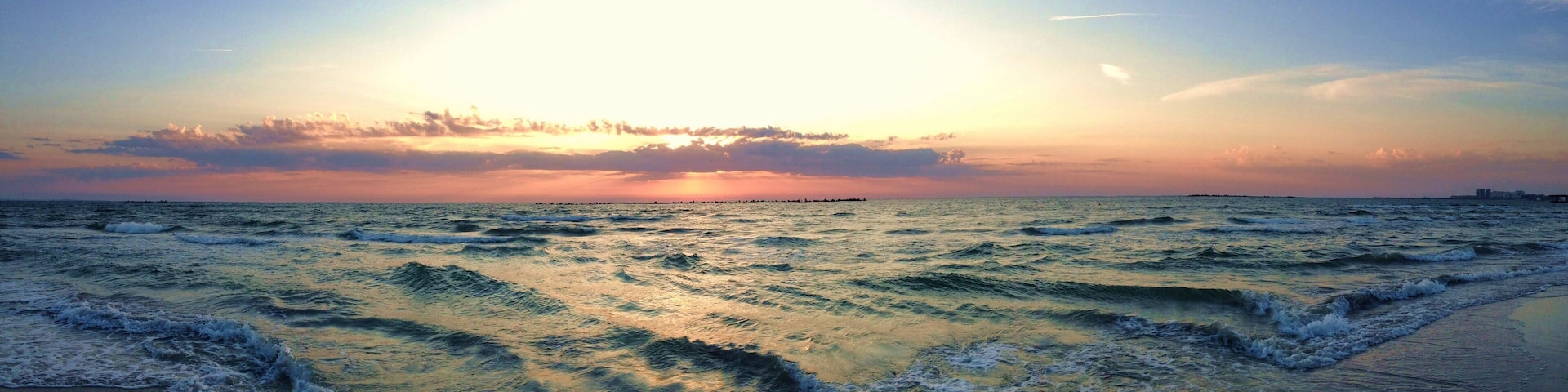 A sunset over the ocean with waves crashing onto the shore.