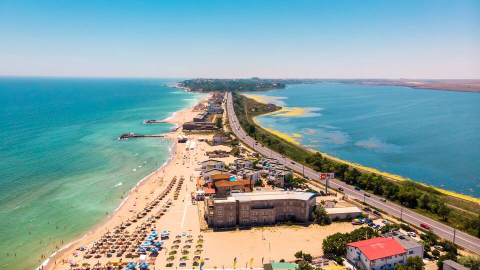 A coastal town with a beach, a road, and a clear blue sea.