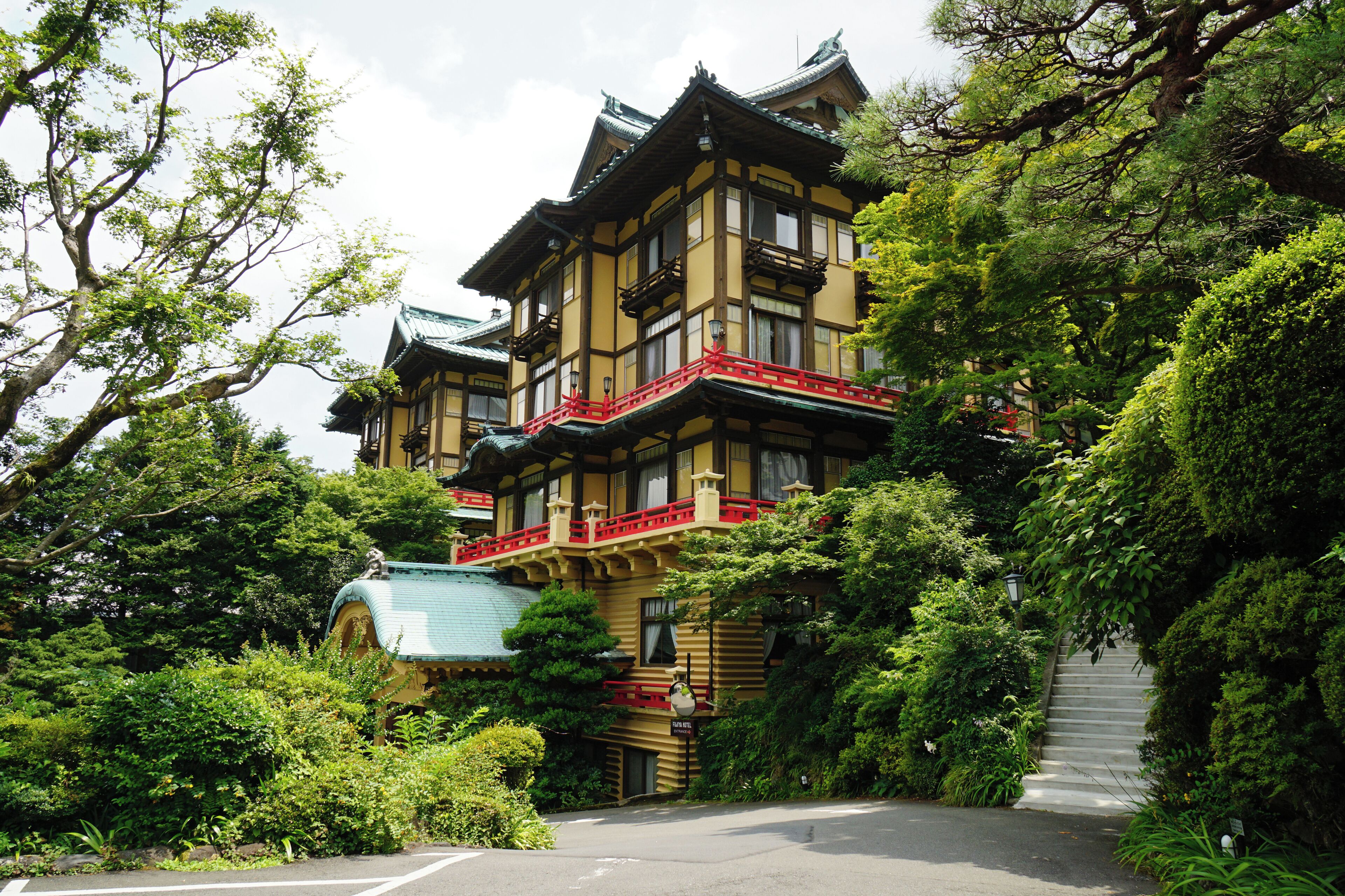 A traditional Japanese building surrounded by lush greenery and a stone staircase.
