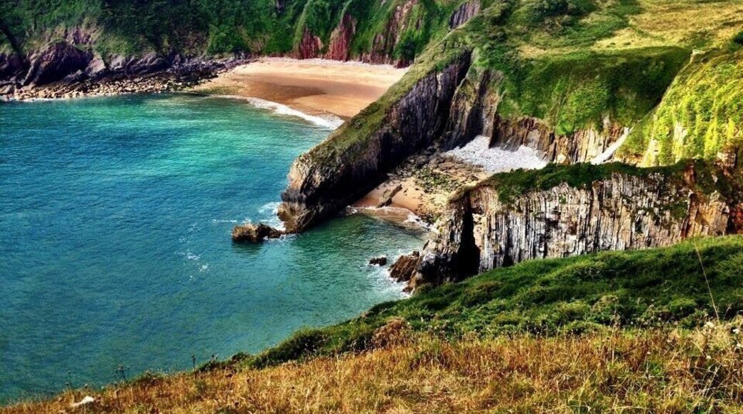Welsh coastal path-Pembrokeshire in South Wales. The bigger beach in the back is only accessible by swimming from the smaller beach in the foreground, or by a hole in the huge rock barrier, only passable at low tide. Early August is a good time to go. It's always been warm (for Wales) and sunny at least 90% of the times I've spent down there. (Pic from August 2014). #beach