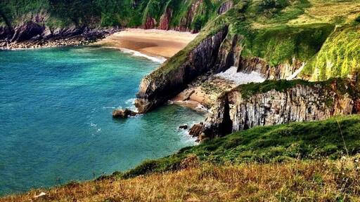 Welsh coastal path-Pembrokeshire in South Wales. The bigger beach in the back is only accessible by swimming from the smaller beach in the foreground, or by a hole in the huge rock barrier, only passable at low tide. Early August is a good time to go. It's always been warm (for Wales) and sunny at least 90% of the times I've spent down there. (Pic from August 2014). #beach