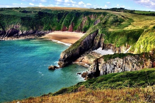 Welsh coastal path-Pembrokeshire in South Wales. The bigger beach in the back is only accessible by swimming from the smaller beach in the foreground, or by a hole in the huge rock barrier, only passable at low tide. Early August is a good time to go. It's always been warm (for Wales) and sunny at least 90% of the times I've spent down there. (Pic from August 2014). #beach
