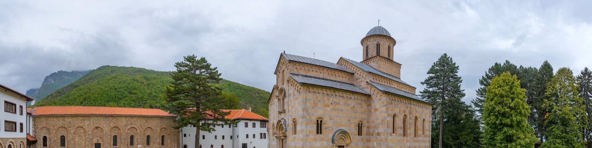 A historic building with a bell tower, surrounded by a well-maintained lawn and stone pathways.