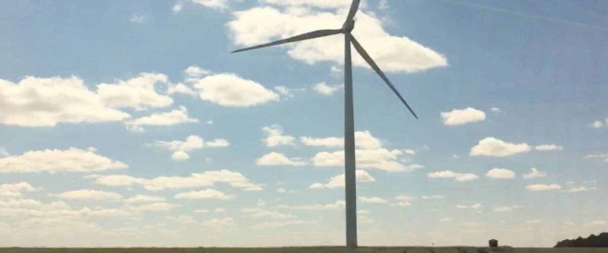 A wind turbine in a field with a clear sky.