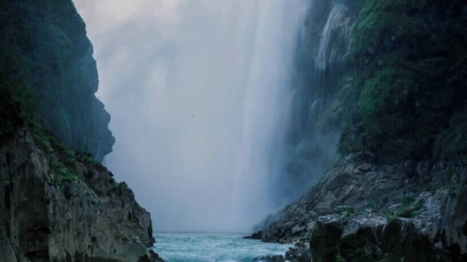 A waterfall cascading down a rocky cliff into a river.