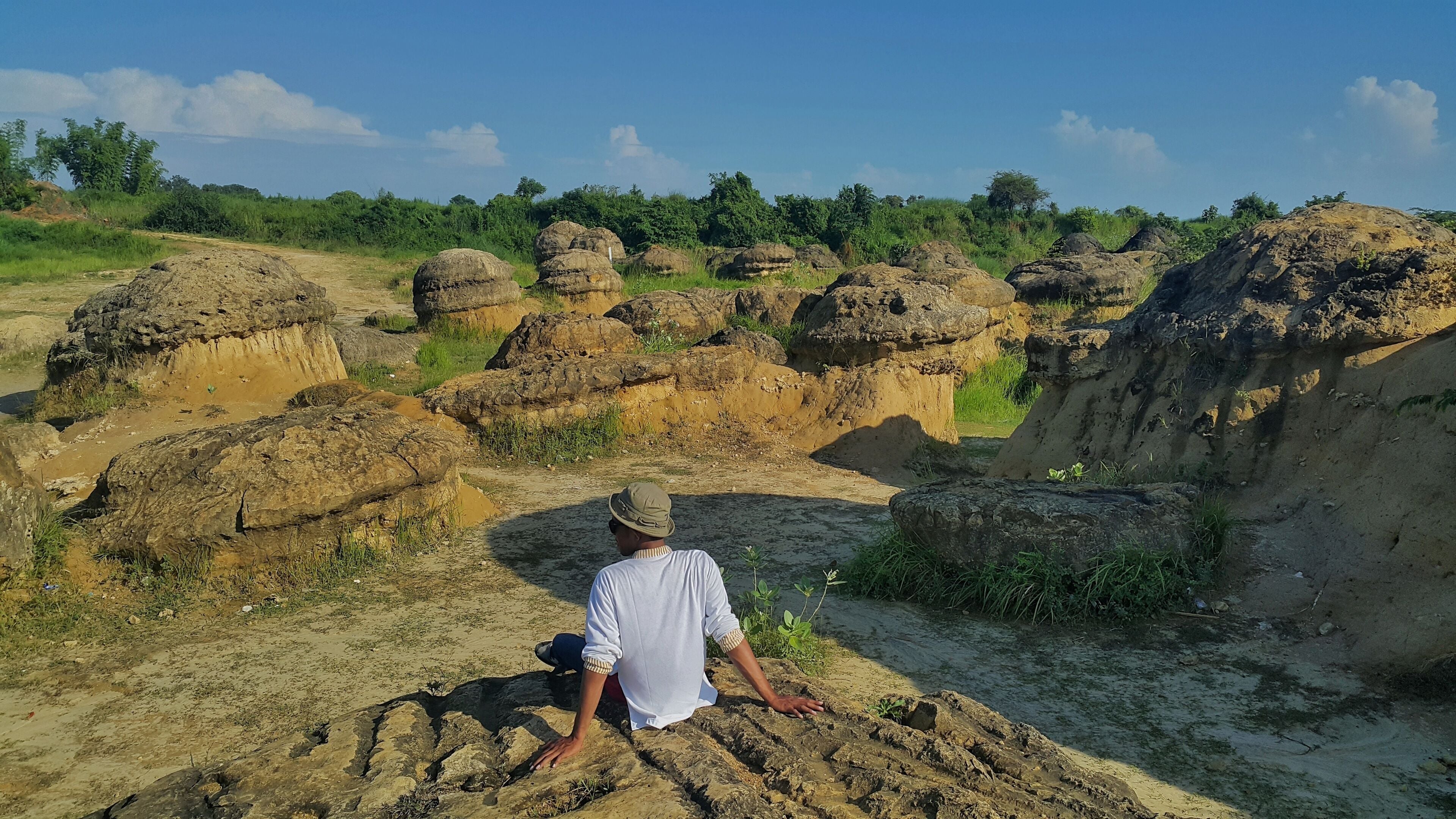 A person sitting on a rocky outcrop overlooking a landscape of large, rounded rock formations.