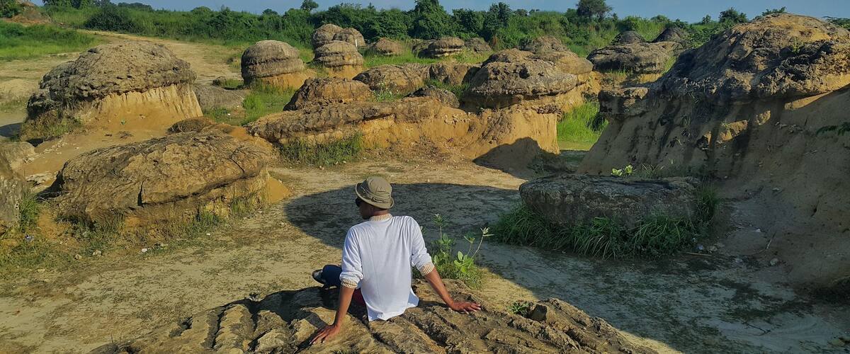 A person sitting on a rocky outcrop overlooking a landscape of large, rounded rock formations.