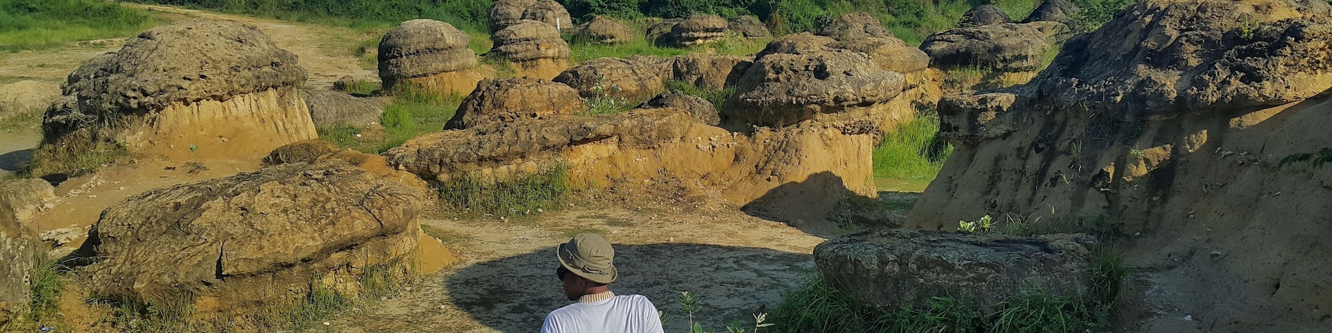 A person sitting on a rocky outcrop overlooking a landscape of large, rounded rock formations.