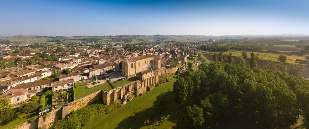 A historic town with a prominent church, surrounded by lush greenery and a river.