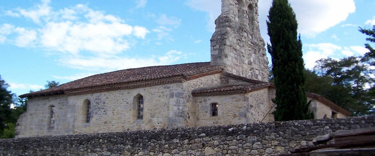 A stone building with a tiled roof and a tall, narrow tower.