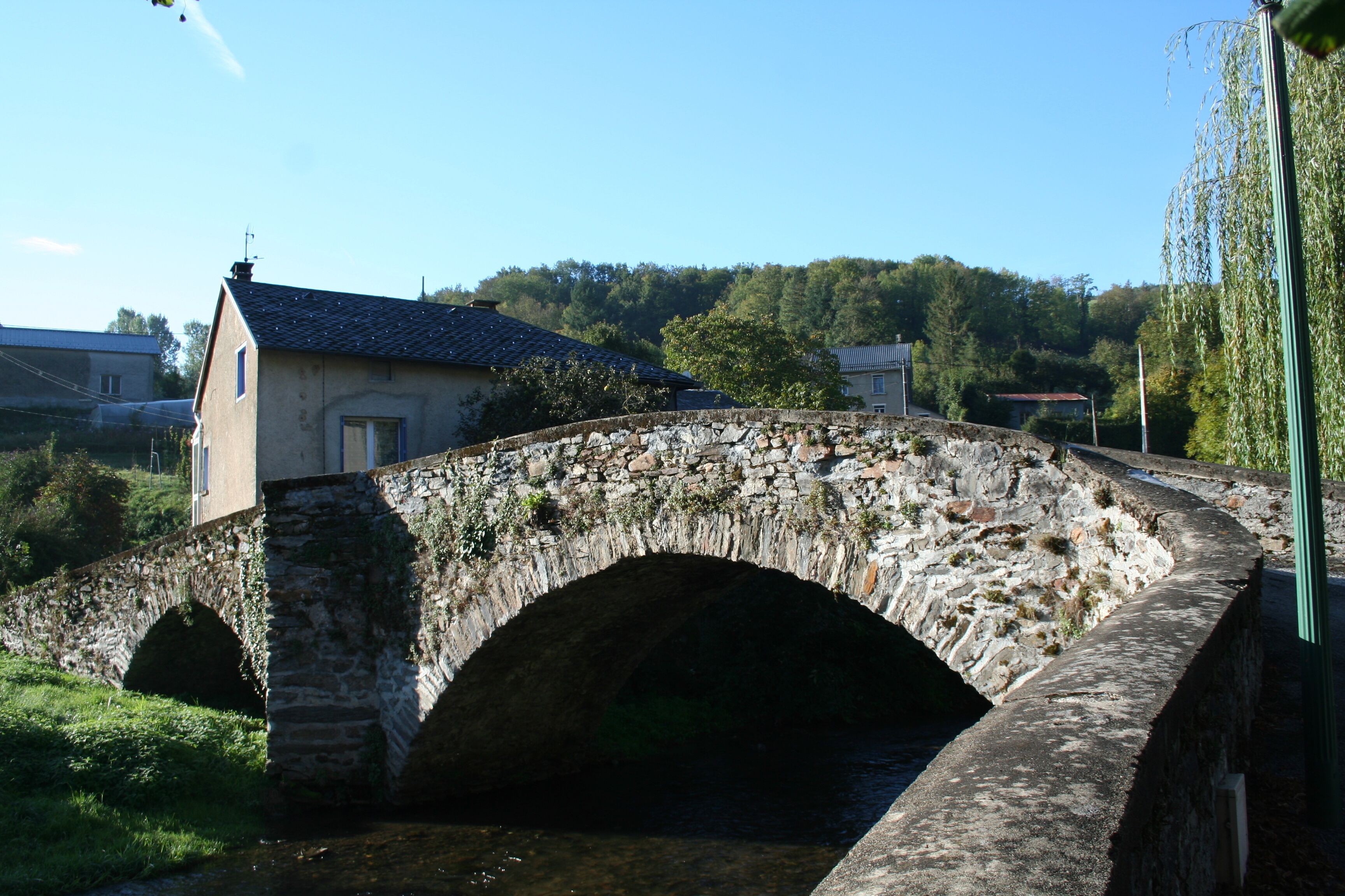 A stone bridge over a river, surrounded by greenery and buildings.