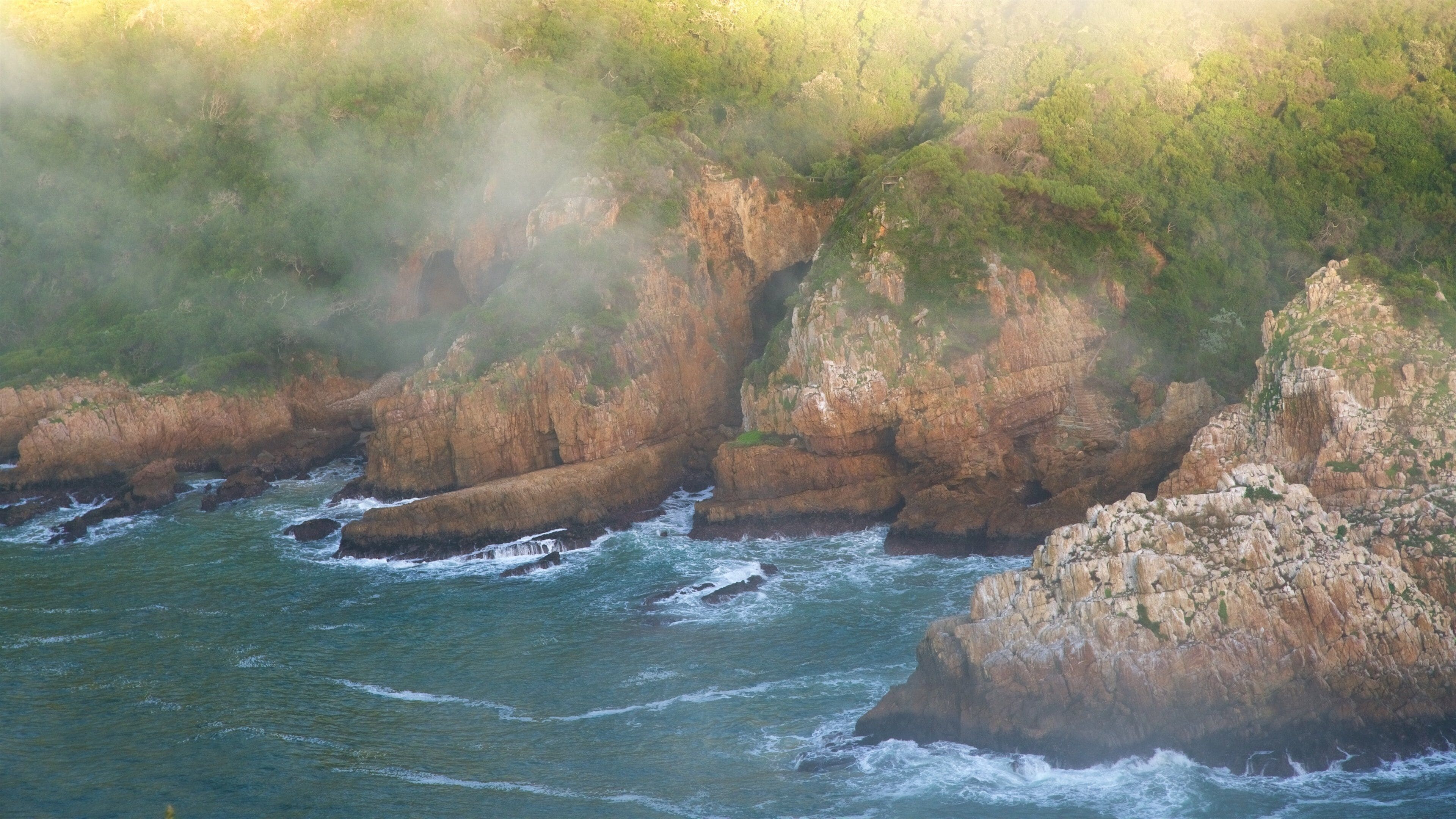 A coastal landscape with rocky cliffs and turbulent sea waves.