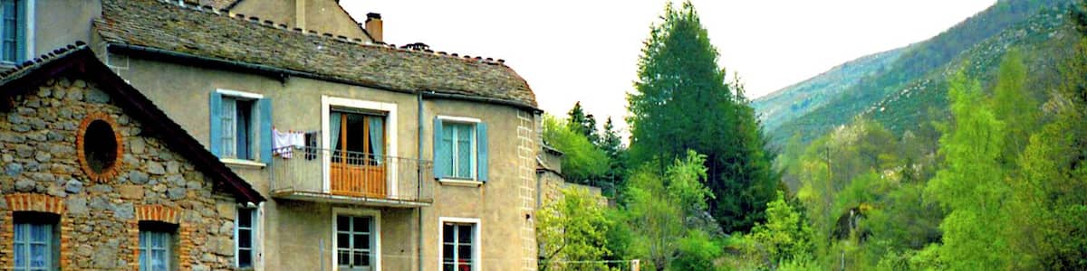 Ein Steinhaus mit einem Balkon mit Blick auf einen Fluss und einen Wasserfall.