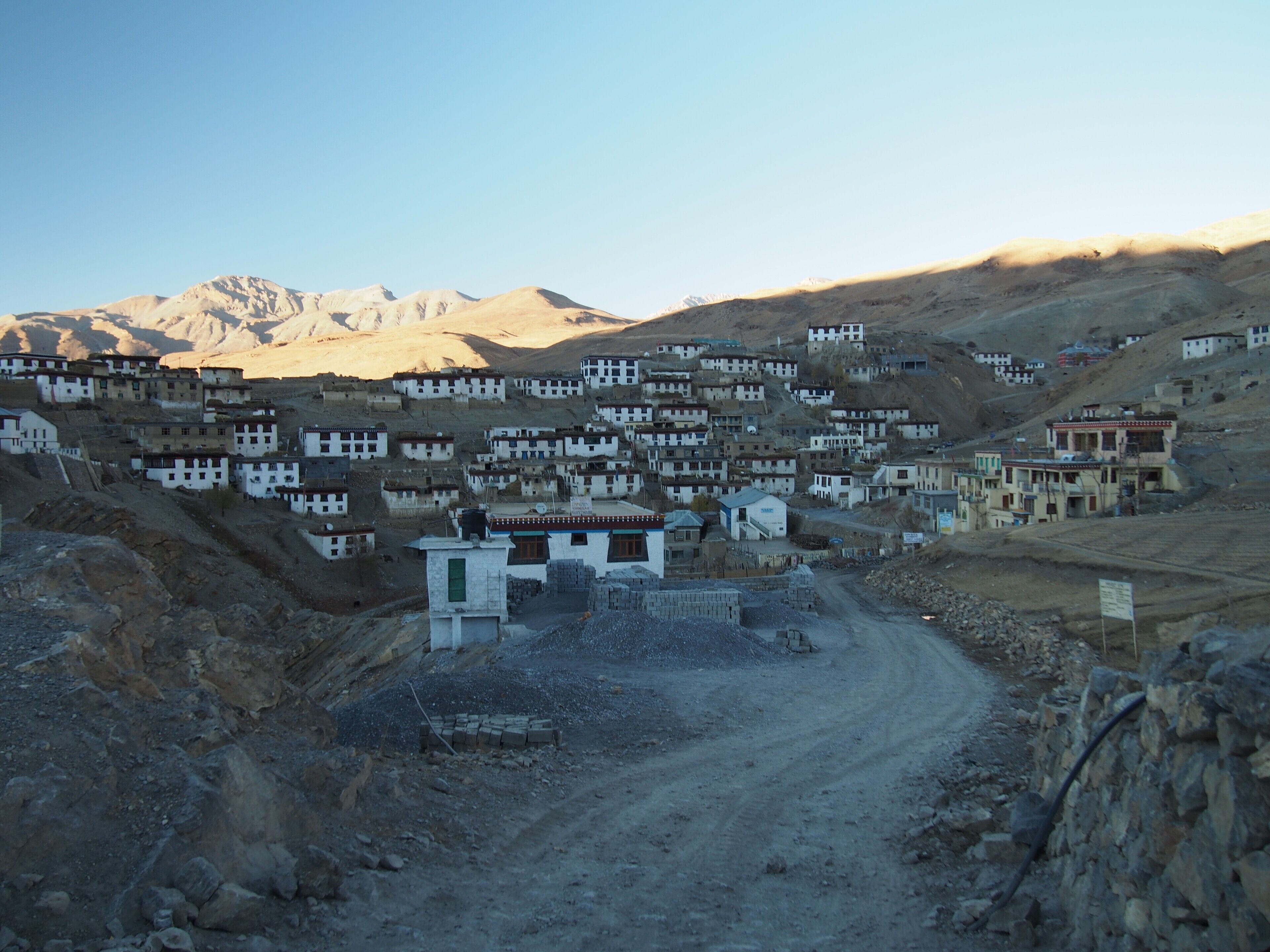 A mountainous village with traditional buildings and a dirt road.