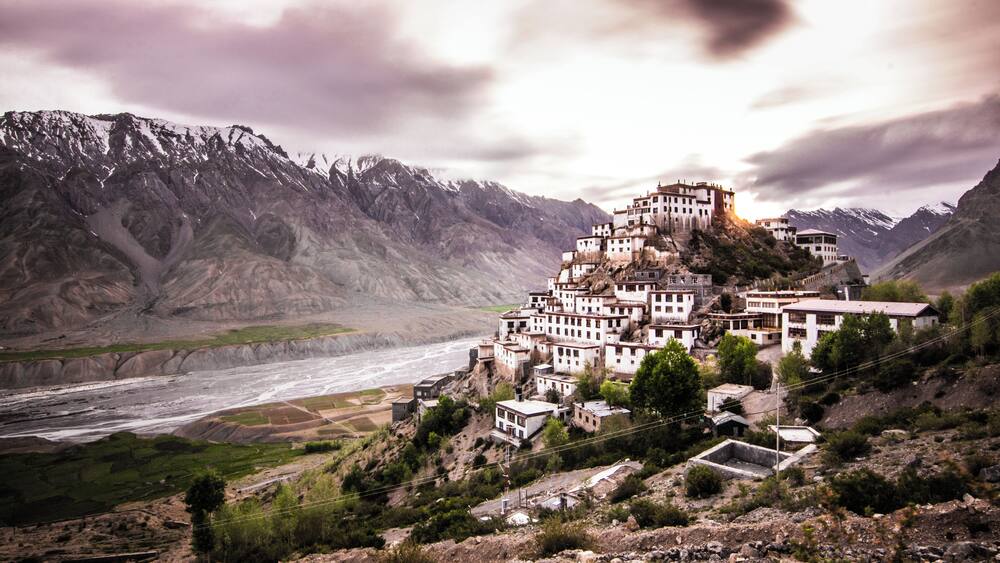A mountainous village with buildings perched on a cliff overlooking a river.