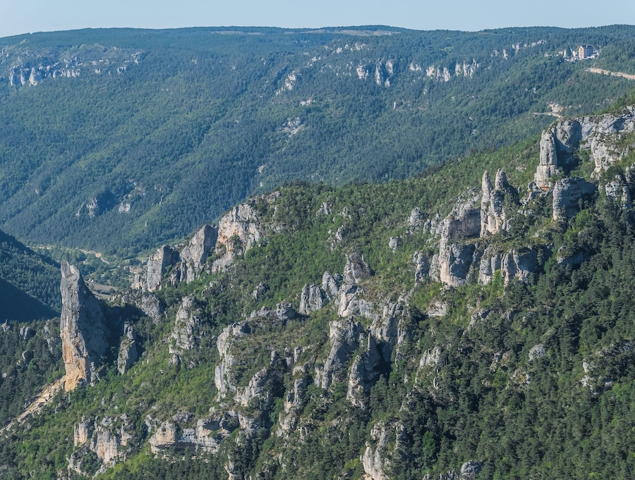 A mountainous landscape with rocky cliffs and dense forest.