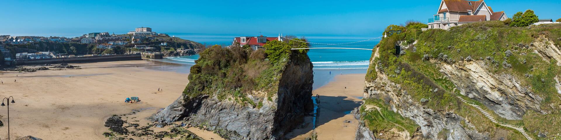 A coastal landscape with a prominent cliff, beach, and a bridge connecting two land masses.