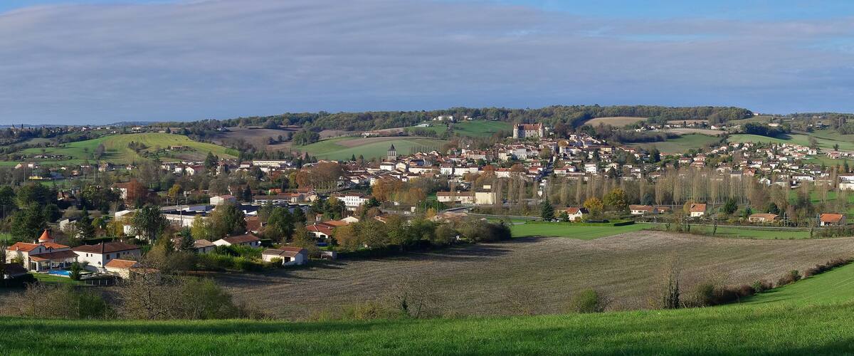 A rural town with rolling hills, fields, and scattered houses.