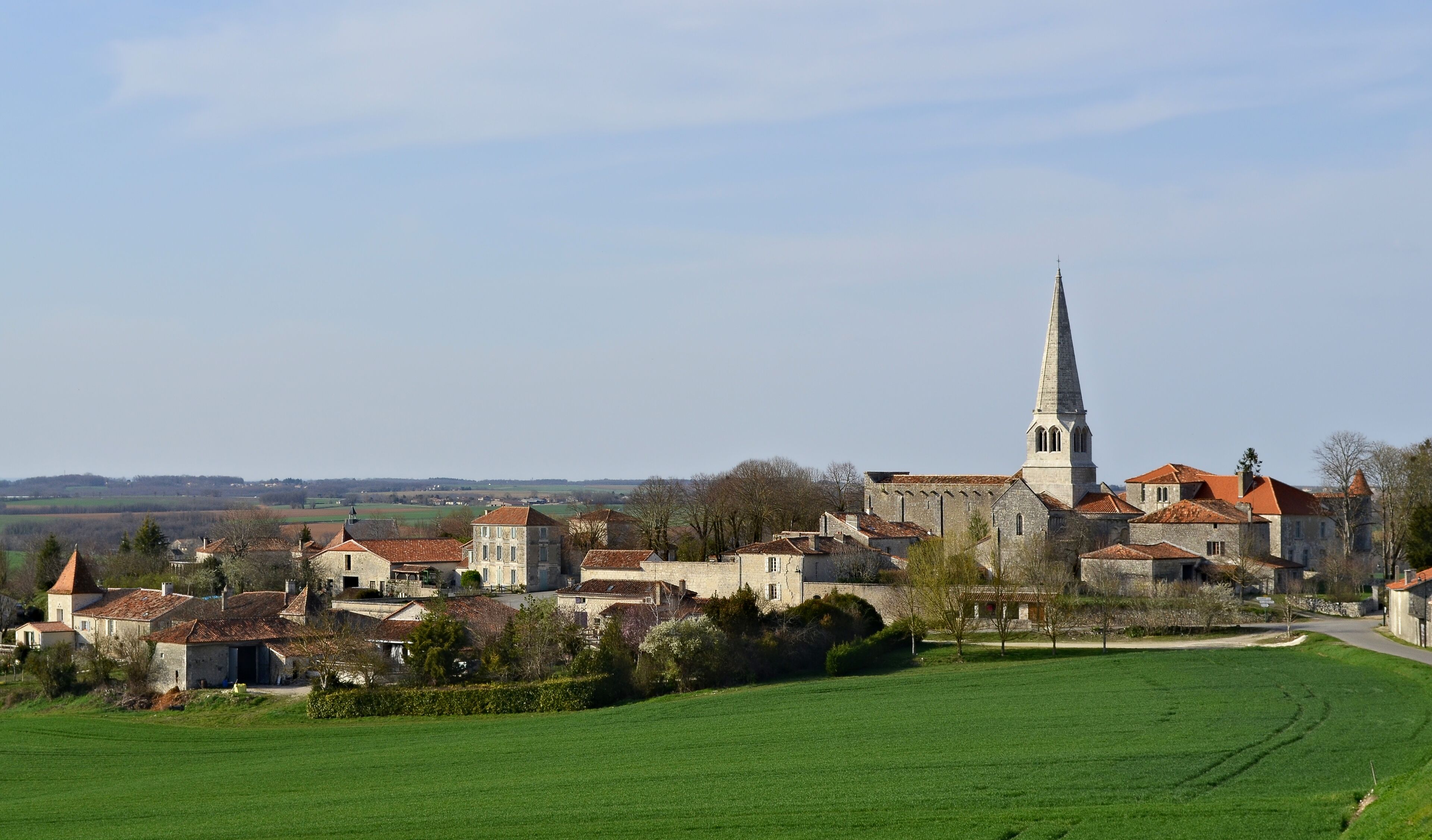 A historic town with a prominent church tower, surrounded by traditional buildings and green fields.