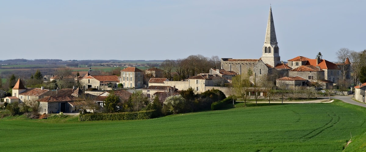 A historic town with a prominent church tower, surrounded by traditional buildings and green fields.