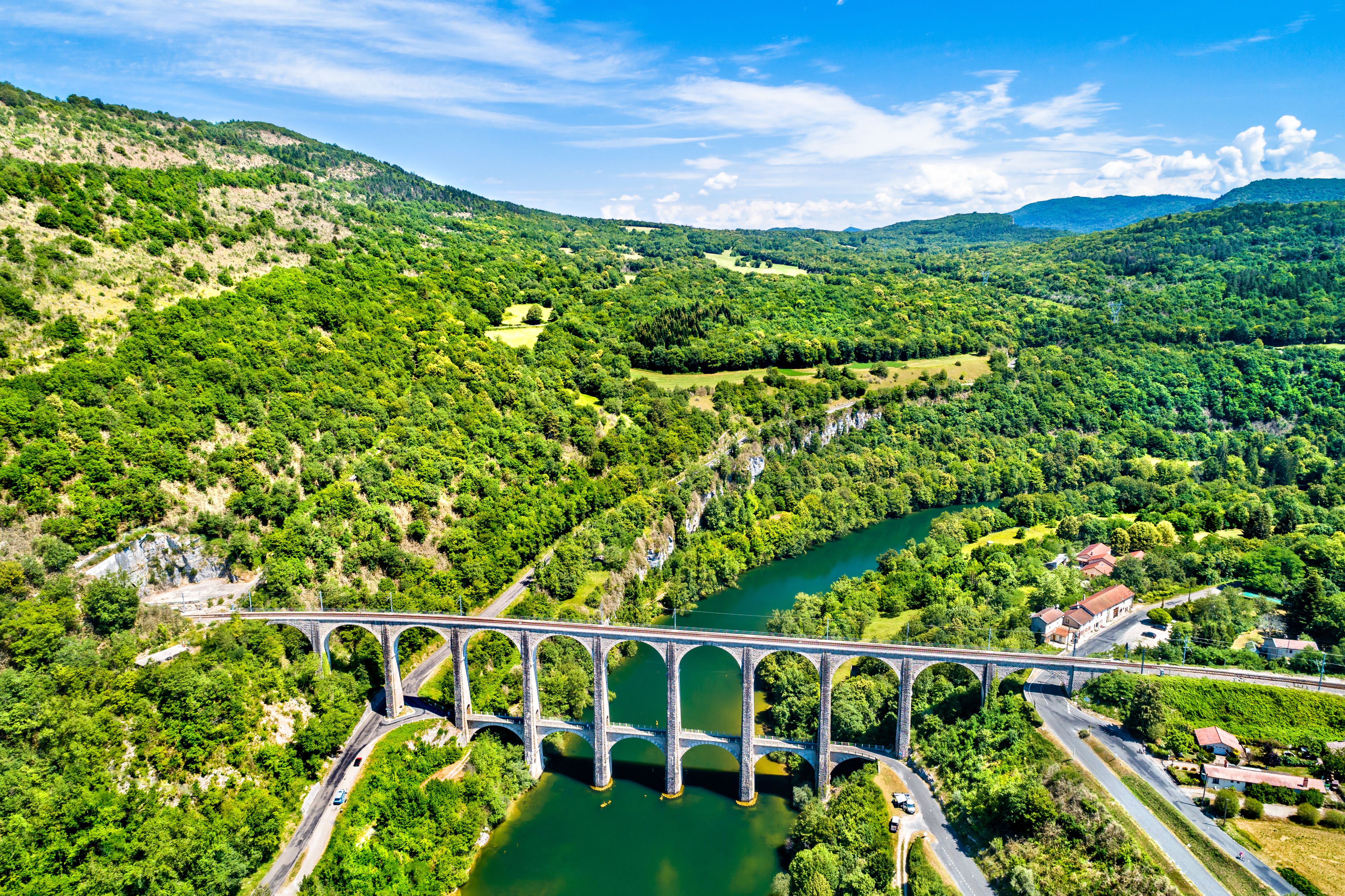 Un pont enjambant une rivière dans une vallée verdoyante et luxuriante, entourée de collines.