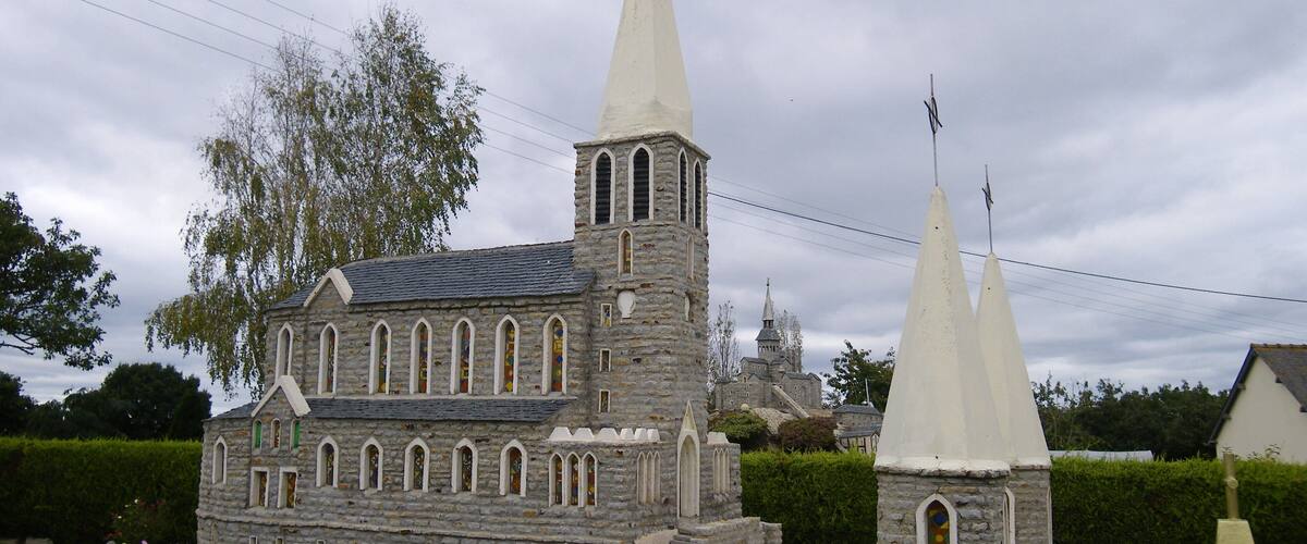 A model of a stone church with two spires and a bell tower.