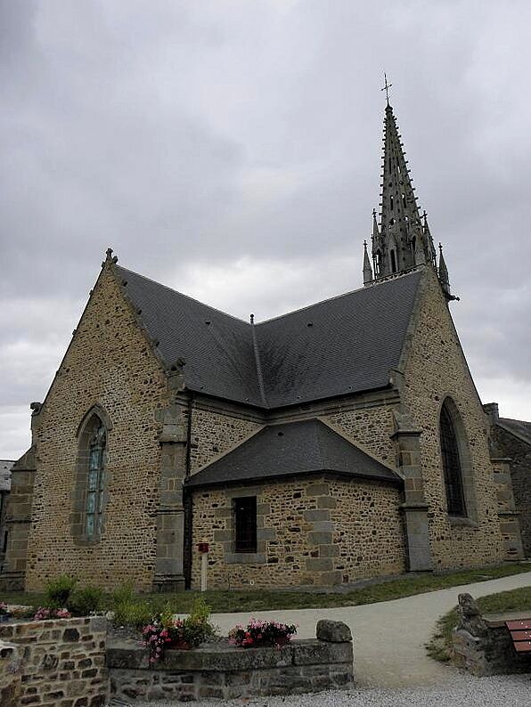 A stone church with a pointed spire and arched windows.