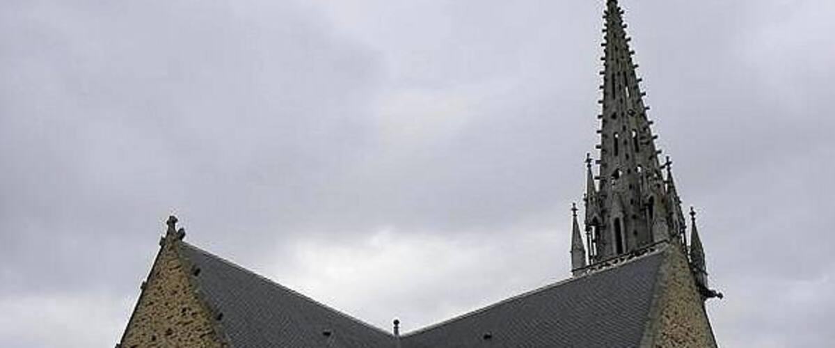 A stone church with a pointed spire and arched windows.
