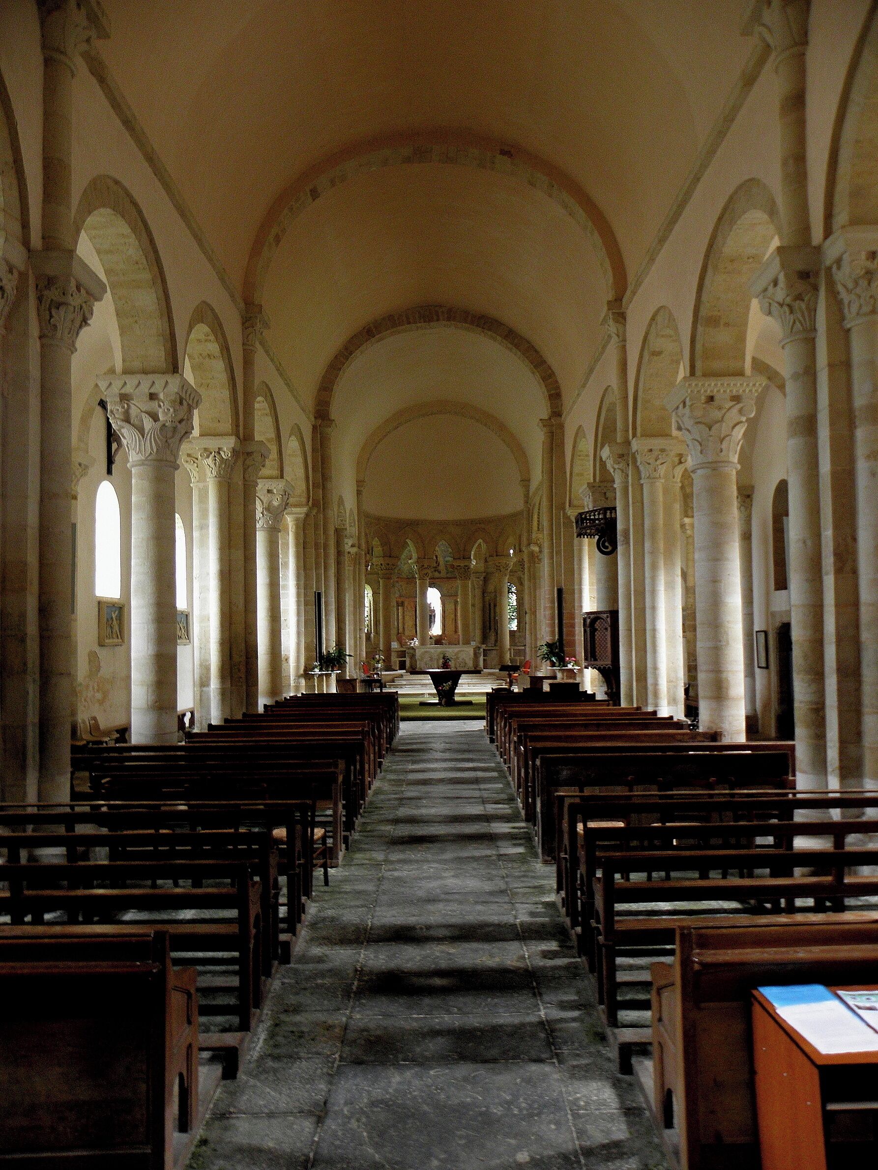 An interior of a church with rows of pews, arched ceilings, and columns.