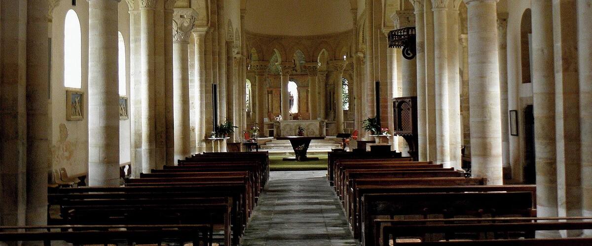 An interior of a church with rows of pews, arched ceilings, and columns.