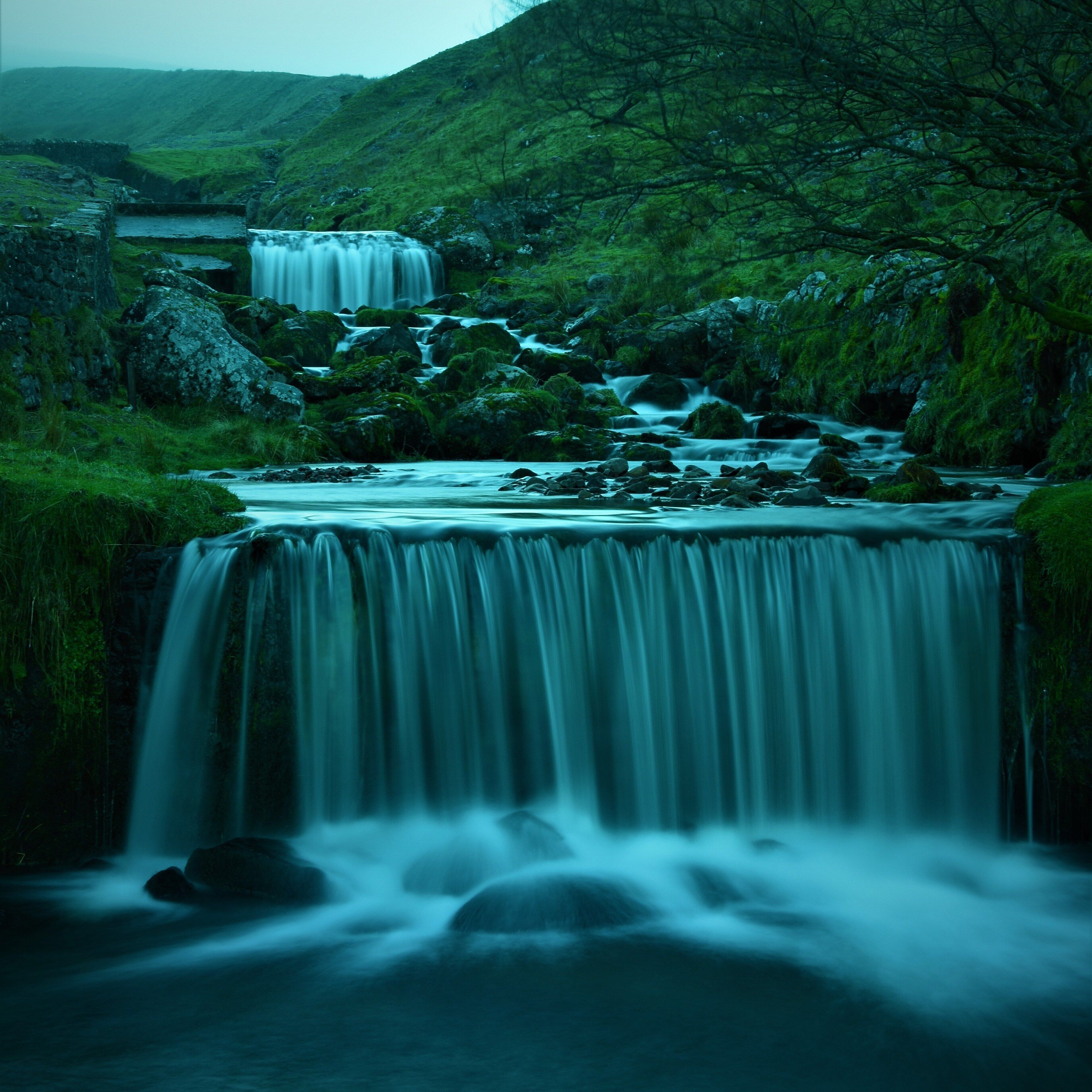 A waterfall cascading over rocks in a lush green valley.